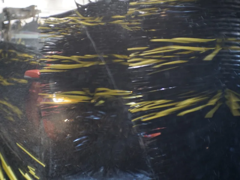 Soft-cloth mitters passing over a car inside the wash tunnel