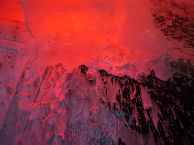 Thick pre-soak foam covering a car under the wash tunnel lights