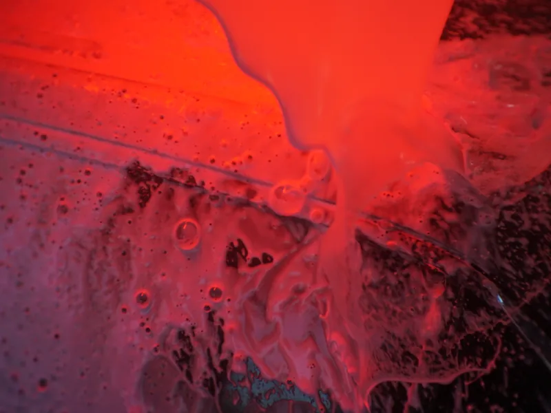 Thick pre-soak foam covering a car under the wash tunnel lights