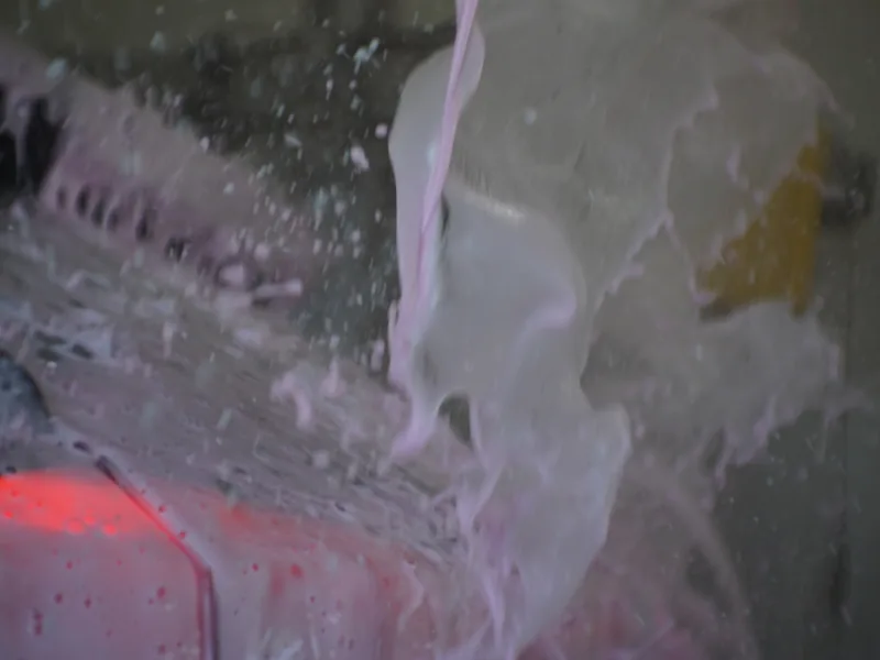 Thick pre-soak foam covering a car under the wash tunnel lights