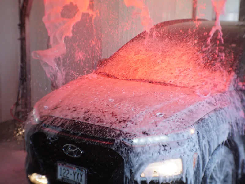 Thick pre-soak foam covering a car under the wash tunnel lights