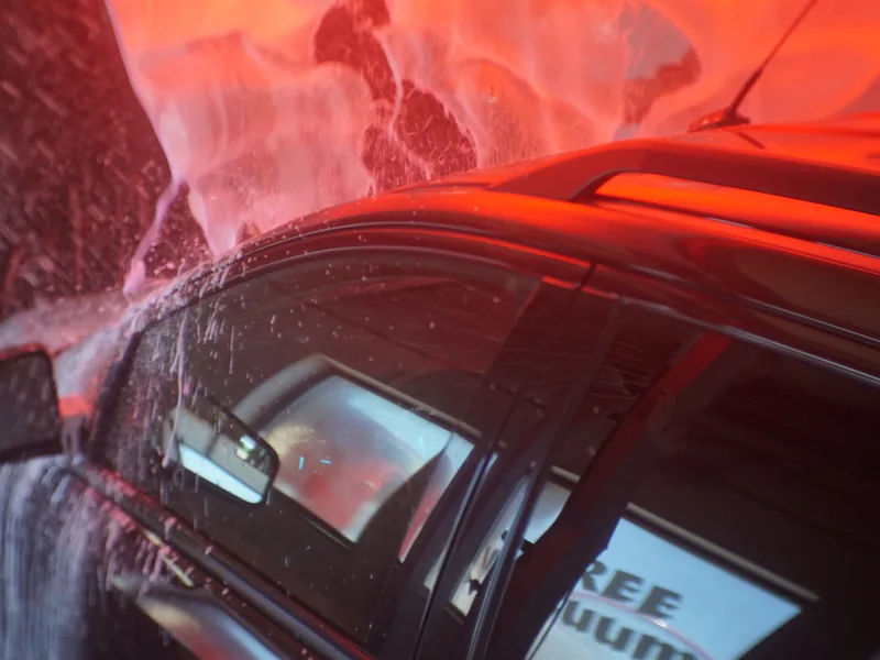Thick pre-soak foam covering a car under the wash tunnel lights