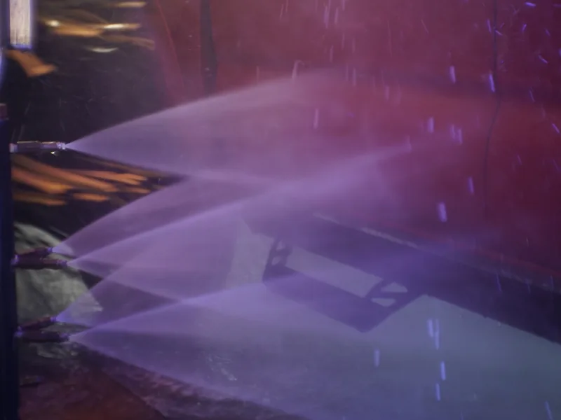 High-pressure rinse spraying down a car in the wash tunnel