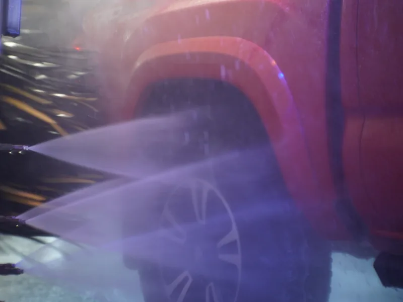 High-pressure rinse spraying down a car in the wash tunnel