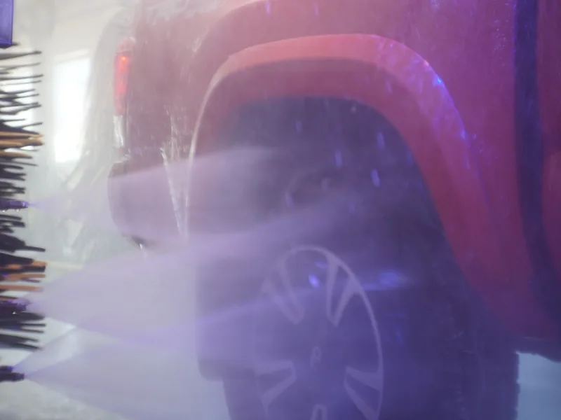 High-pressure rinse spraying down a car in the wash tunnel