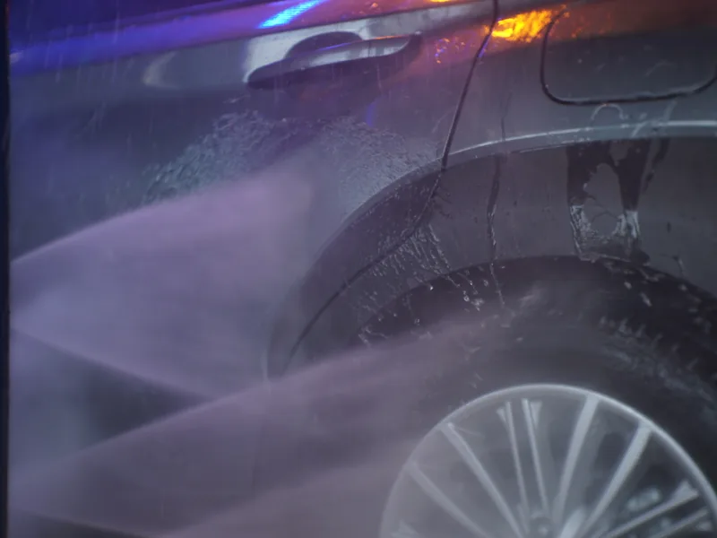 High-pressure rinse spraying down a car in the wash tunnel