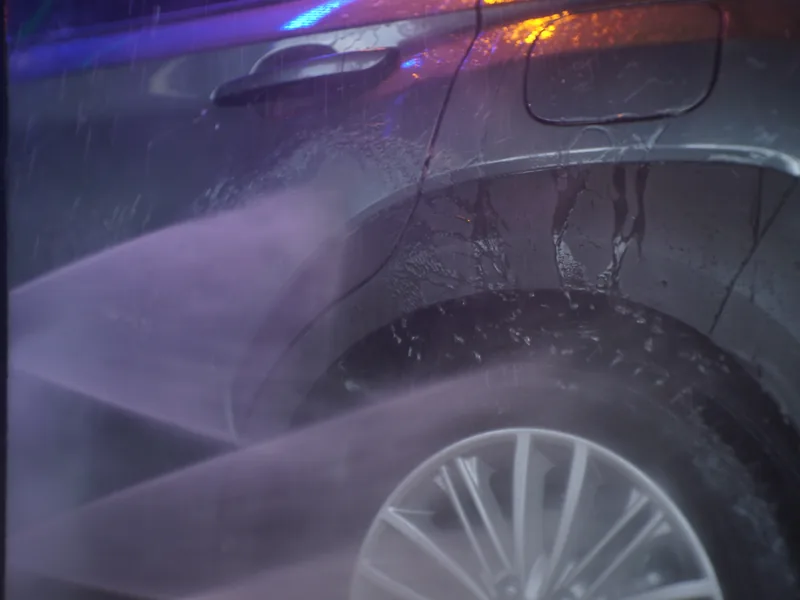 High-pressure rinse spraying down a car in the wash tunnel