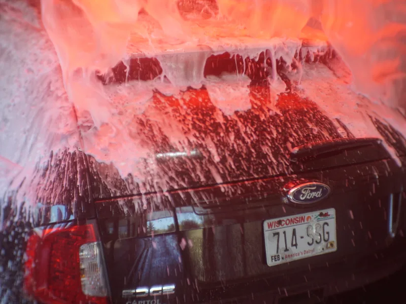 High-pressure rinse spraying down a car in the wash tunnel