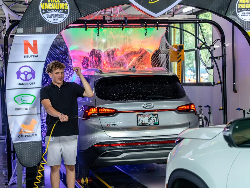 A Mr. Splash team member prepping a car before the wash tunnel at Madison East